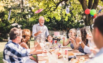 family gathered around long table in backyard celebrating without being bothered by mosquitoes