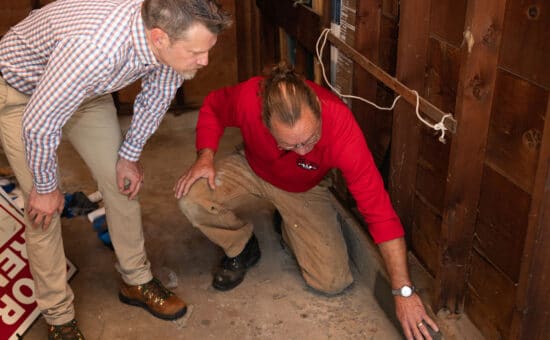 pest control technician showing homeowner hole in garage where mice enter