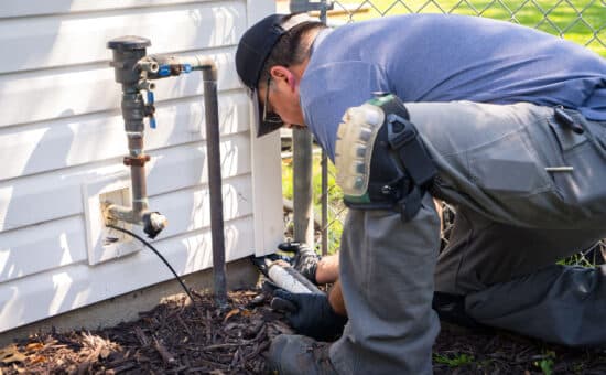Pest control technician sealing up a house