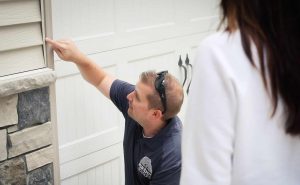 pest control technician pointing to entry points mice use to enter home along garage door